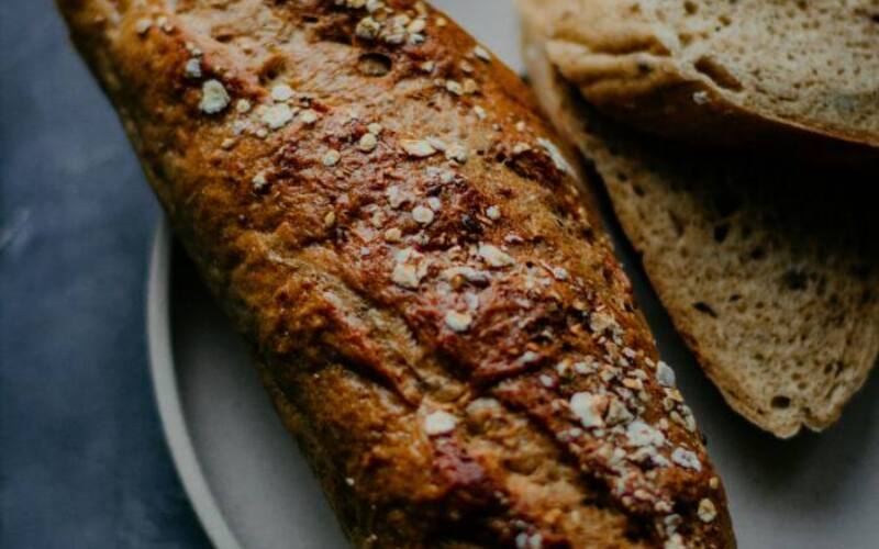 Close-up of homemade whole wheat bread with oats on a plate, dark background.